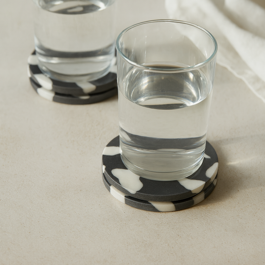 Two glasses of water on black and white striped coasters with a white napkin in the background.