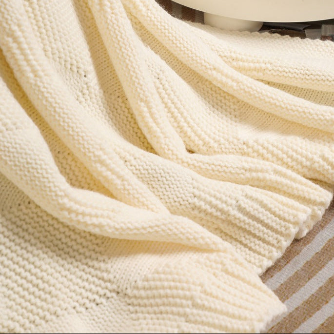 Close-up of a beige knitted blanket draped over a surface.