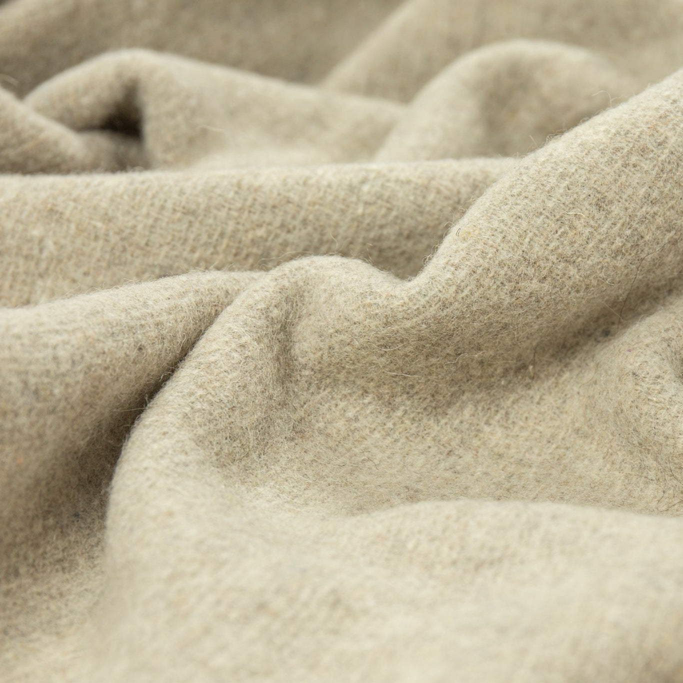 Close-up of beige fabric of a wool throw rug with a textured surface
