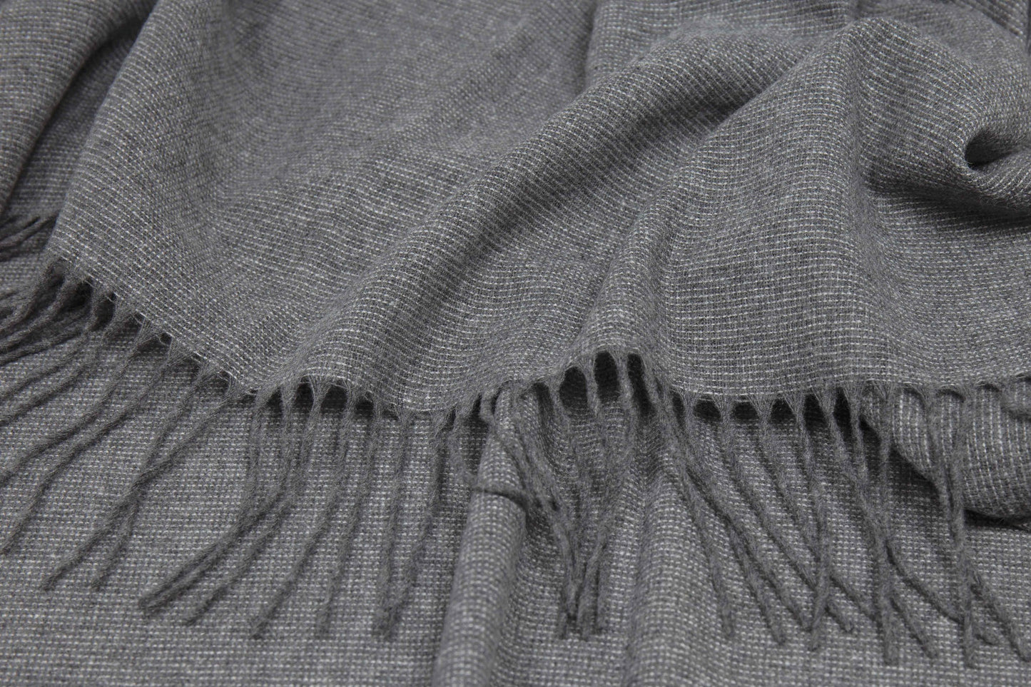 Gray throw rug with fringes close up