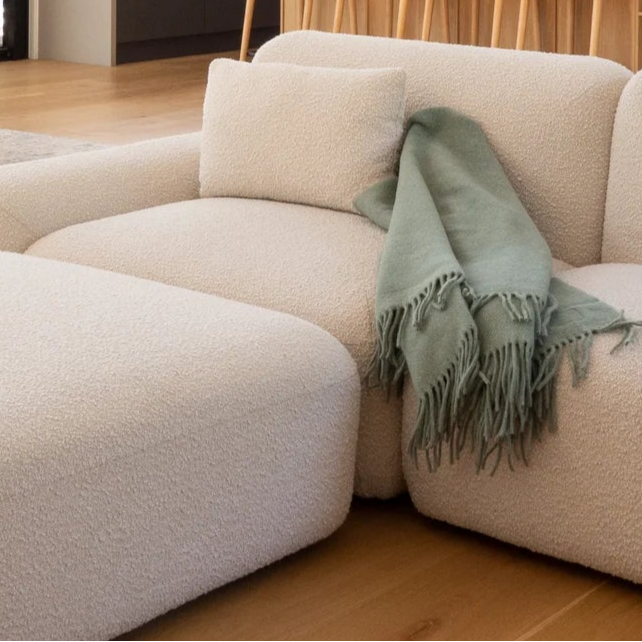 Modern living room with a sectional sofa and sage green throw draped over it