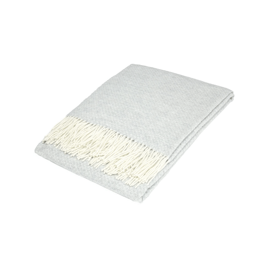 Silver wool throw rug with white tassles folded on white background | Mirra Interiors