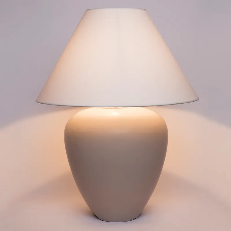 Table lamp with a beige-grey base and white shade showing ambient lighting