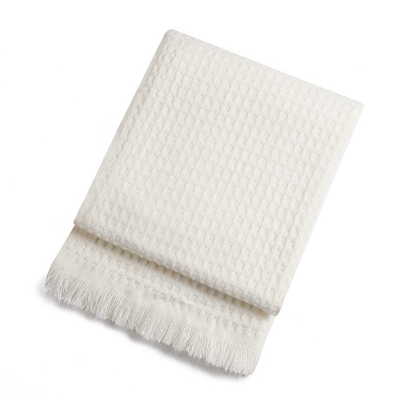 White waffle textured throw blanket with fringe on a white background