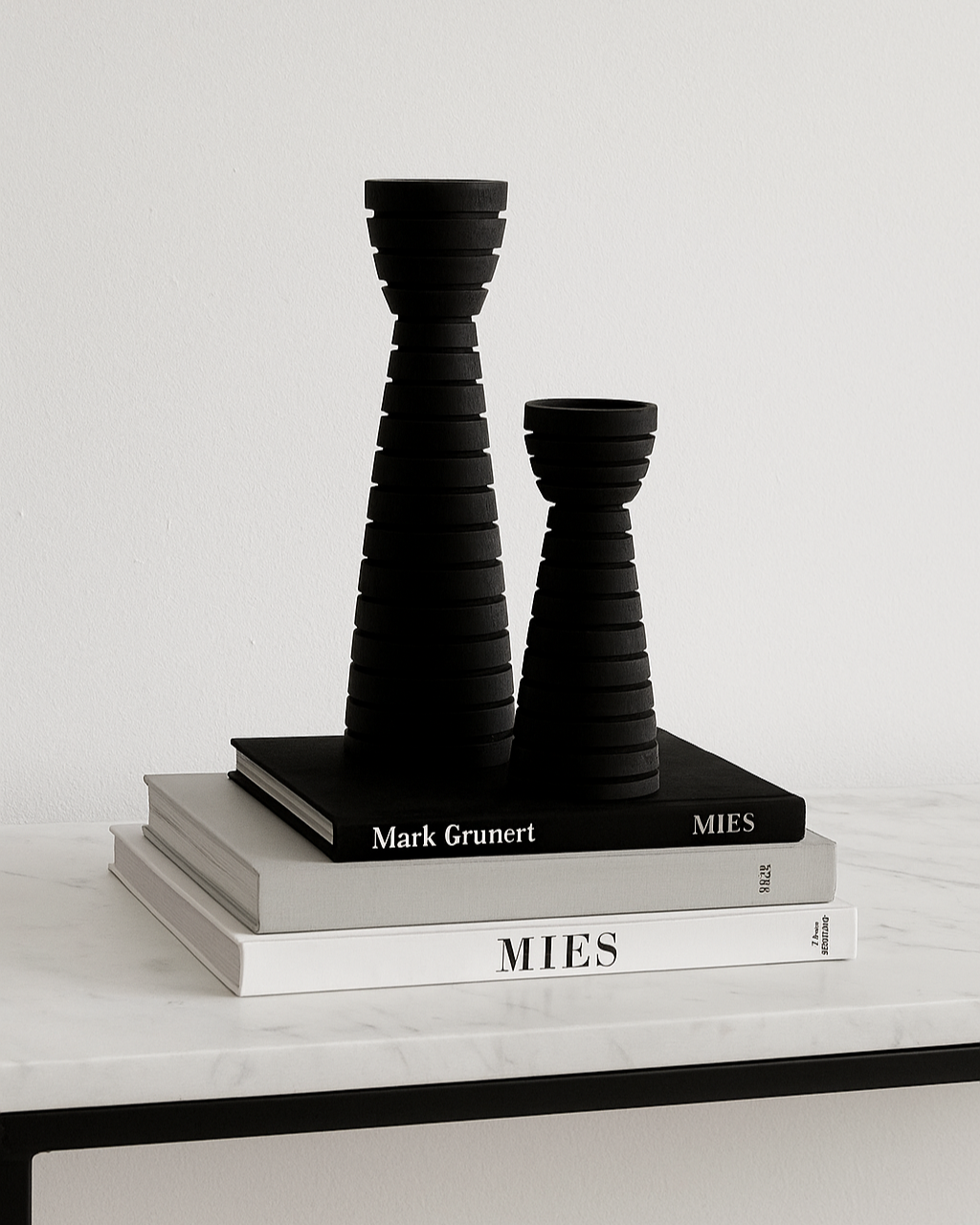 Black carved wood candle holders styled on stack of books on marble console table | Mirra Interiors