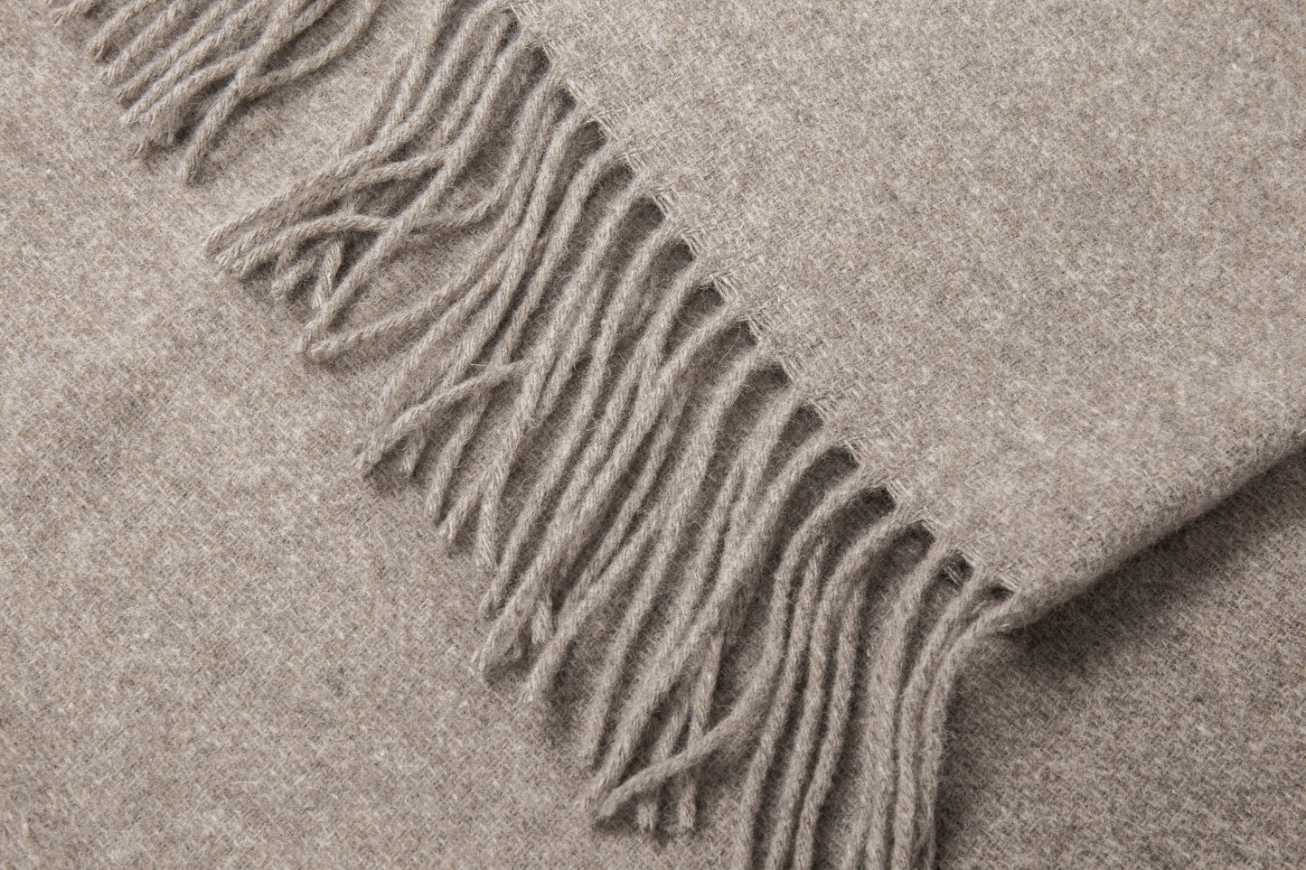 Close-up of a beige blanket with fringes folded texture