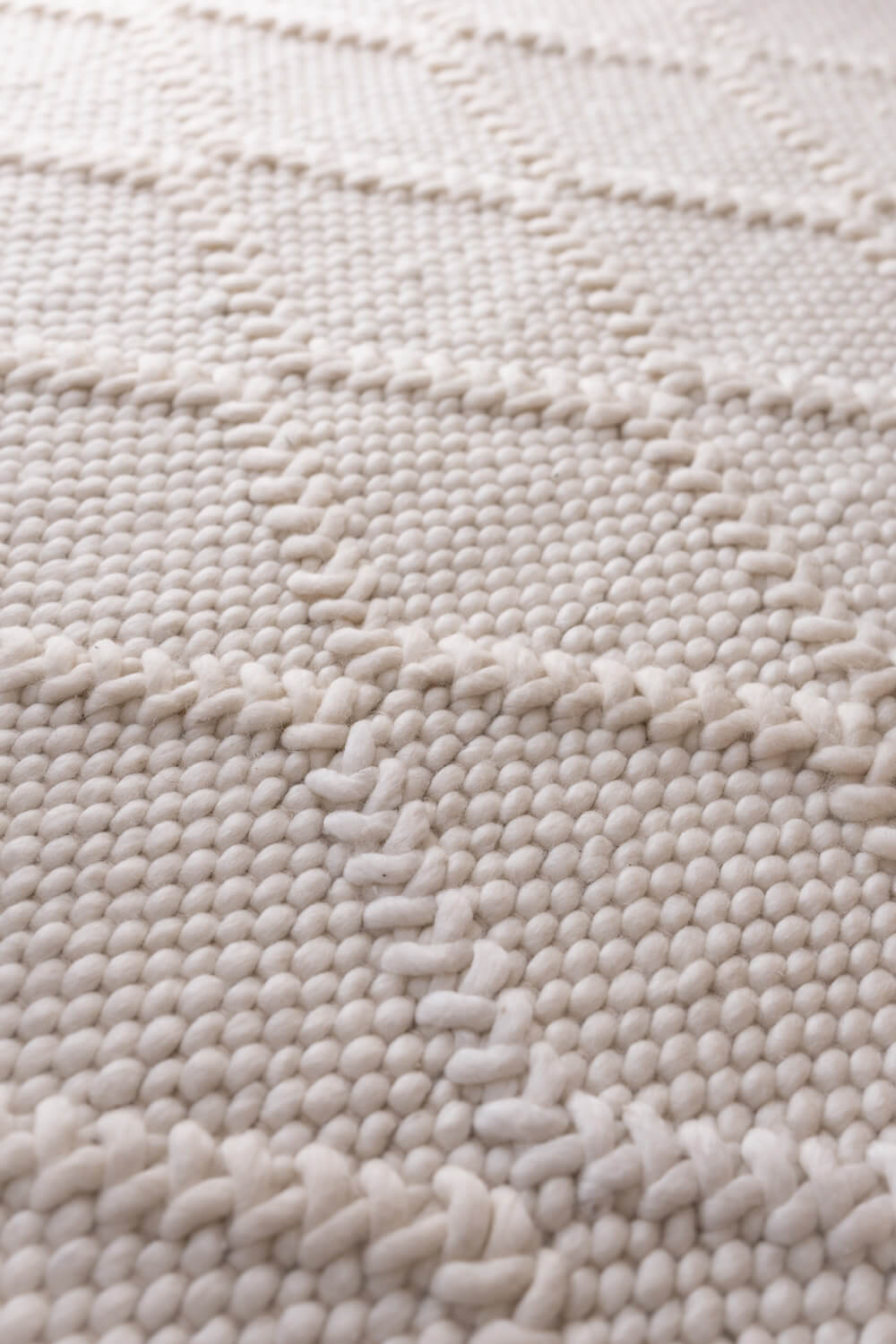 Close-up of a textured beige rug with a wavy pattern