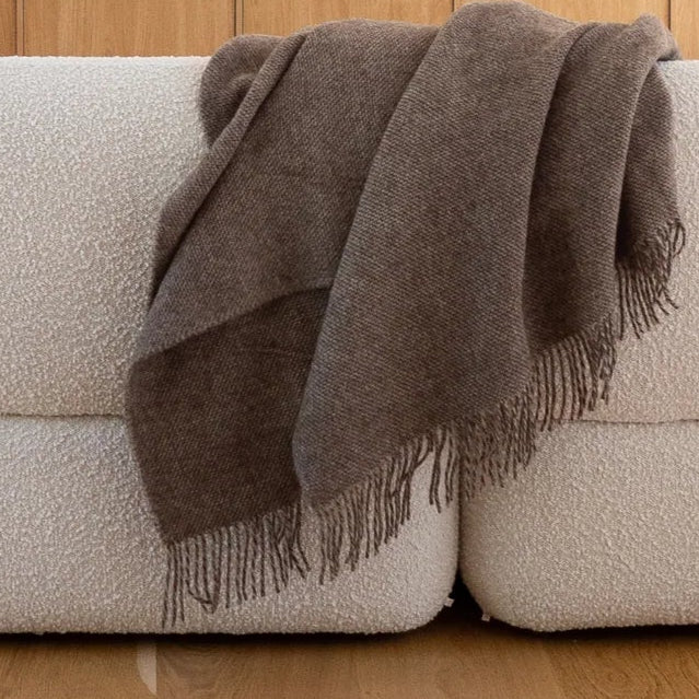 Modern white sofa, with brown blanket on wooden oak flooring