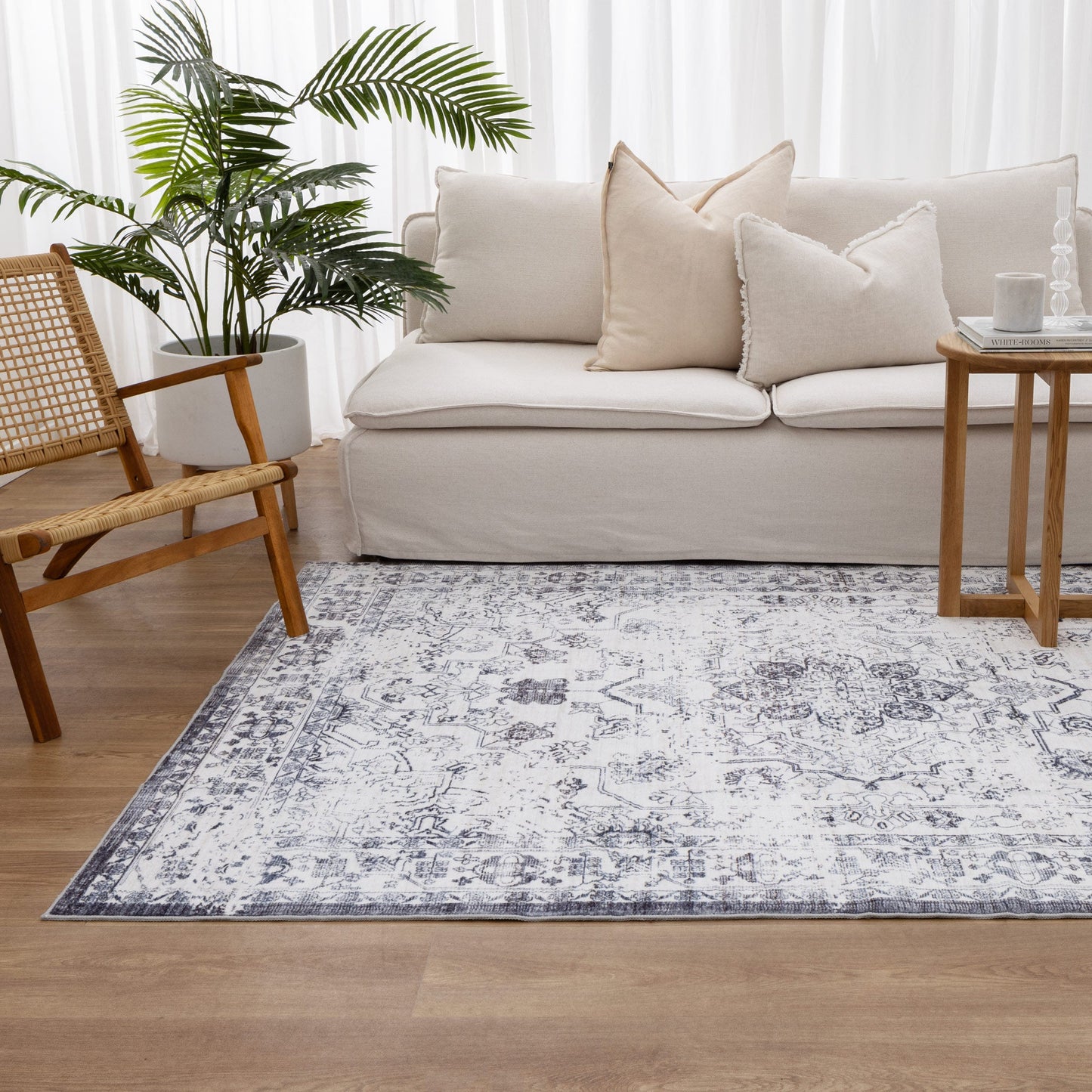 Living room with a beige sofa, wooden chair, and patterned rug.