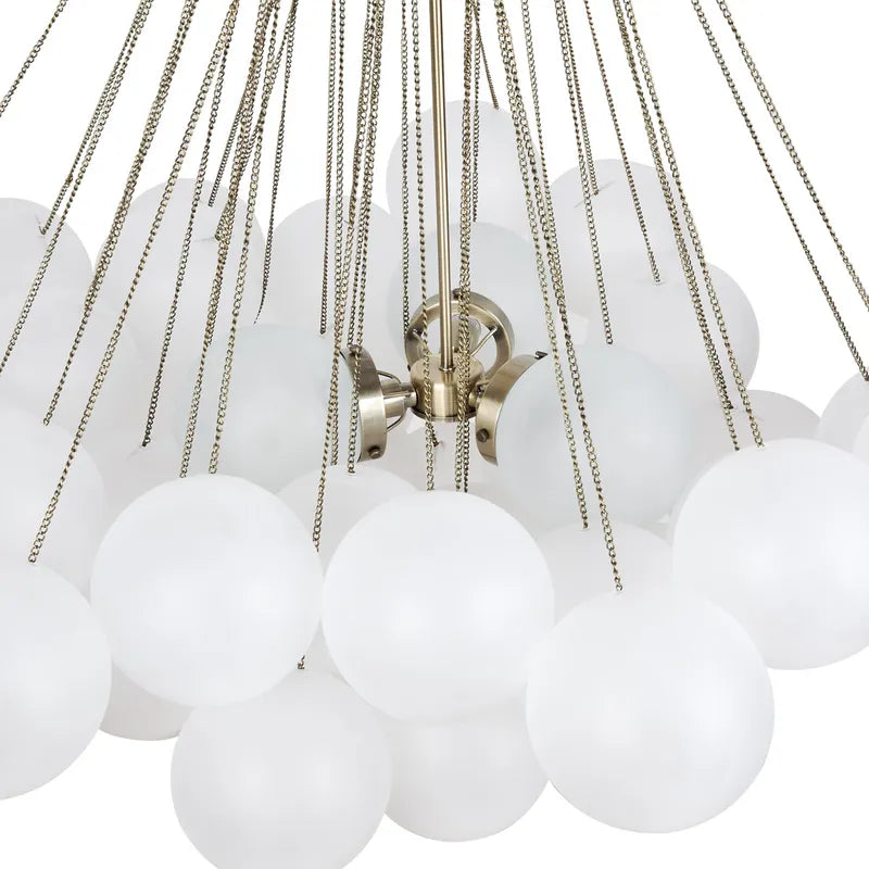 Close-up of a chandelier with white glass balls and brass chains on a white background