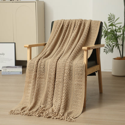 Beige knitted blanket draped over a wooden chair in a room with a plant and cabinet.
