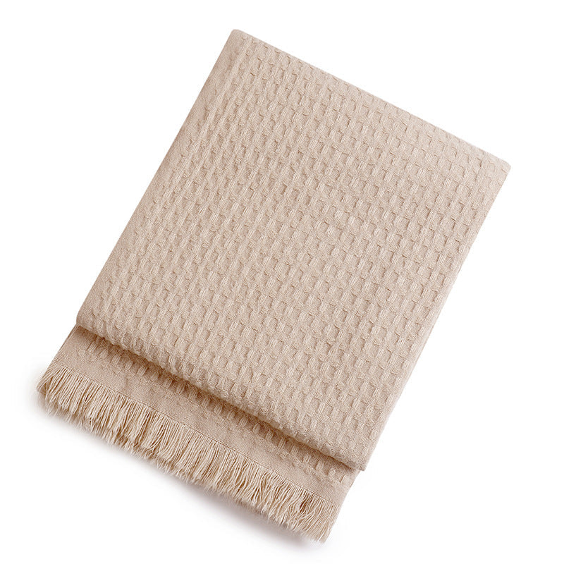 Beige textured throw blanket with fringe on a white background