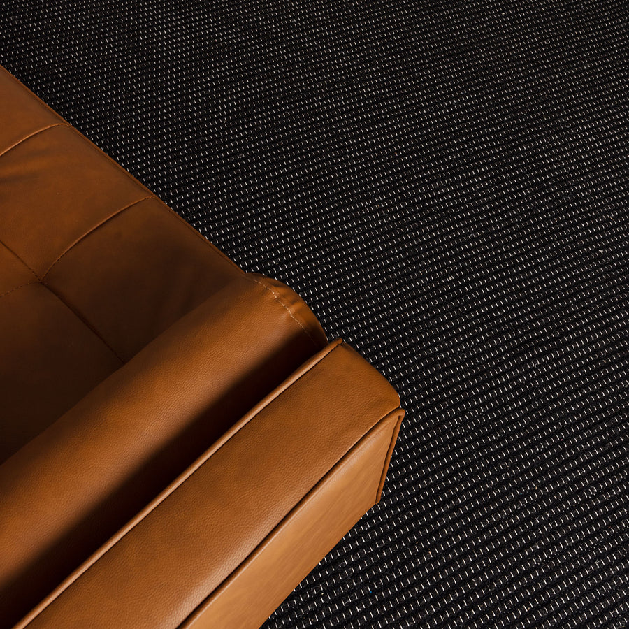 Brown leather sofa corner on a black textured floor