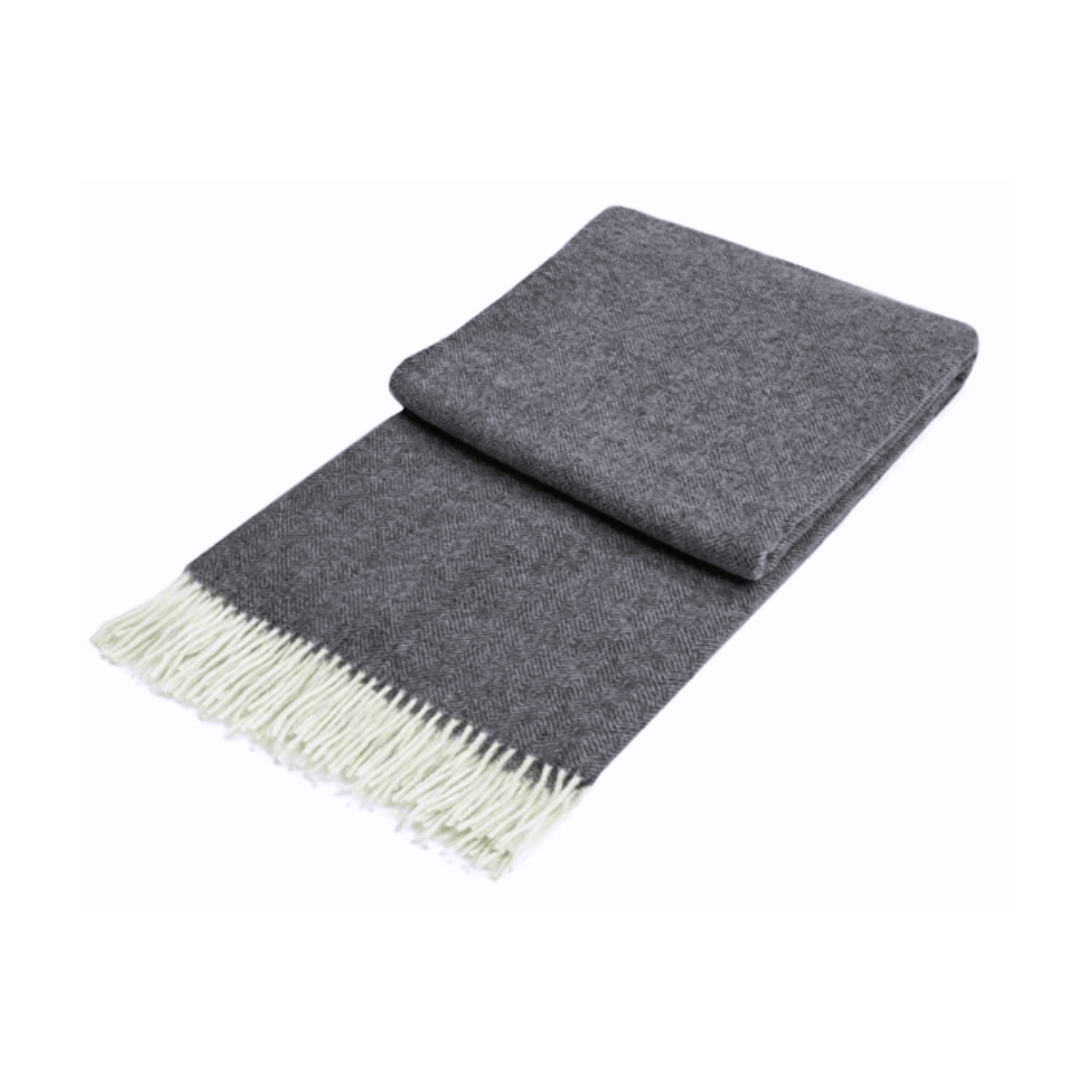 dark grey folded throw rug with diamond pattern and white fringe on white background
