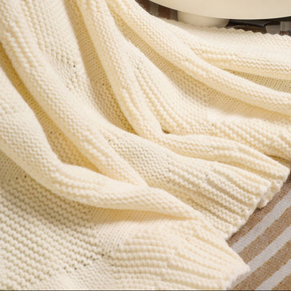 Close-up of a beige knitted blanket draped over a surface.