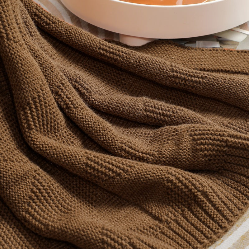 Close-up of a brown knitted throw rug with a blurred background