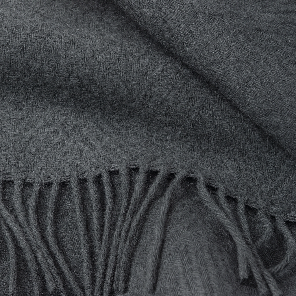 Close-up of a dark gray throw rug with fringed edge