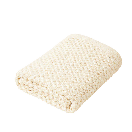 Folded cream knitted blanket on a light beige background