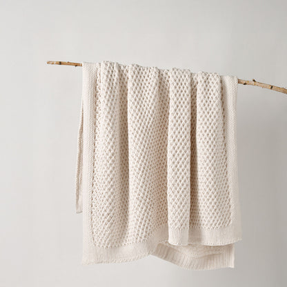 cream textured throw rug hanging on a wooden stick against a white background | Mirra Interiors