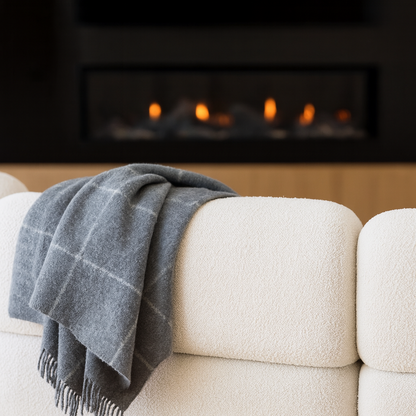 Grey Throw blanket draped over a white sofa with a fireplace in the background