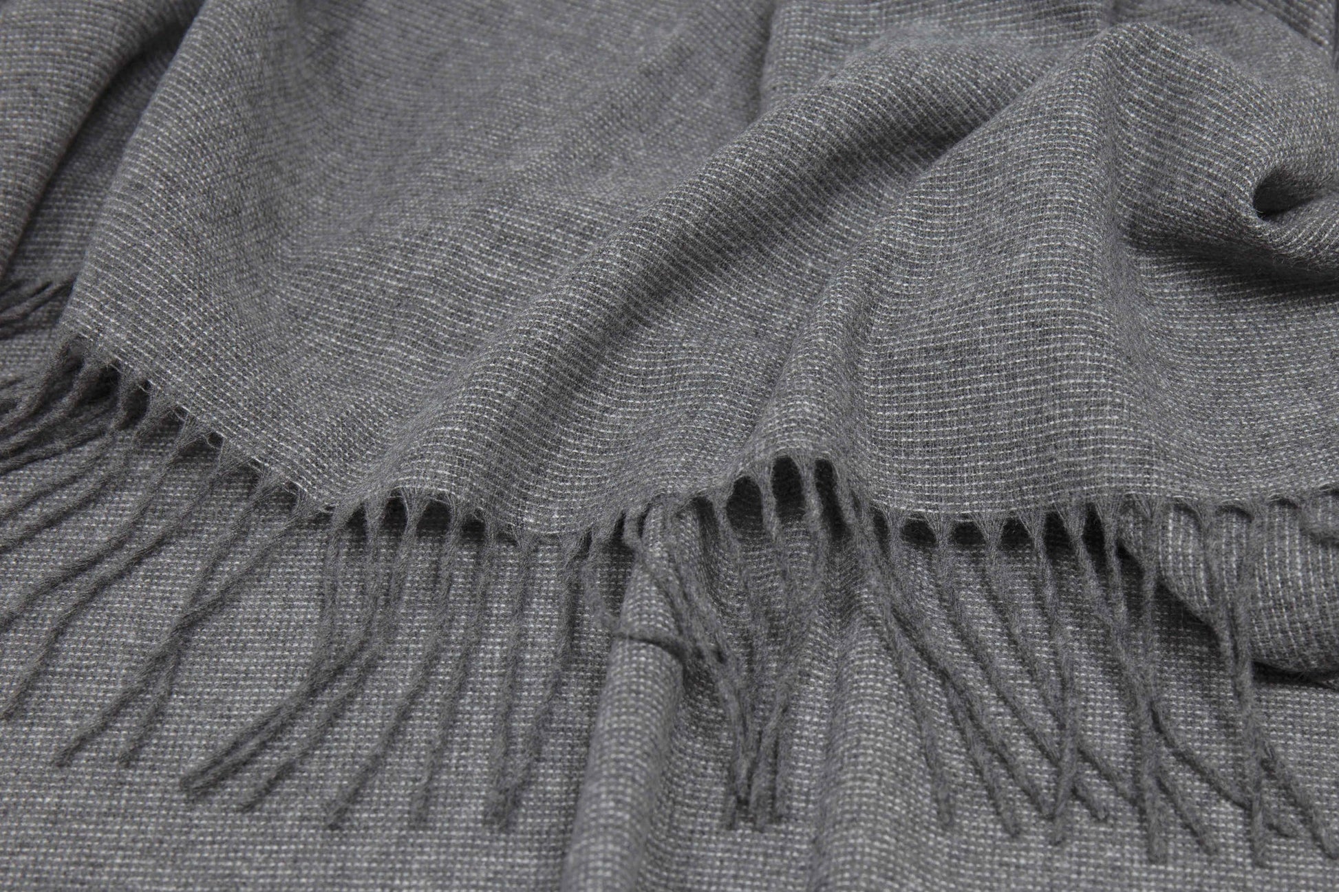 Gray throw rug with fringes close up