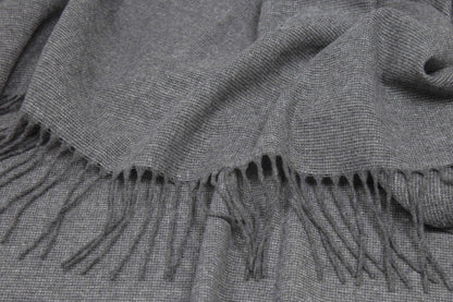 Gray throw rug with fringes close up