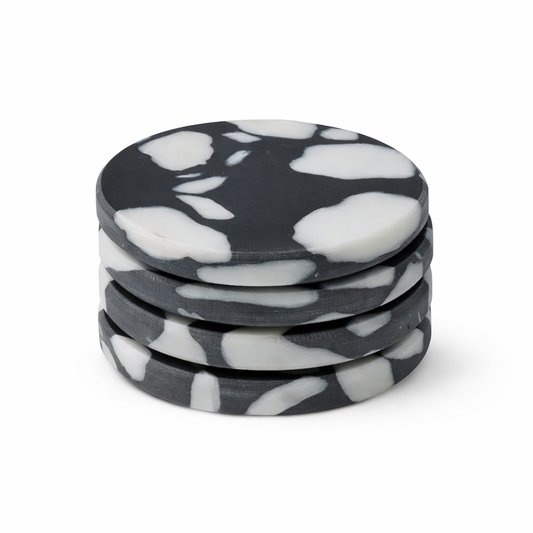 Set of four black and white marbled coasters on a white background