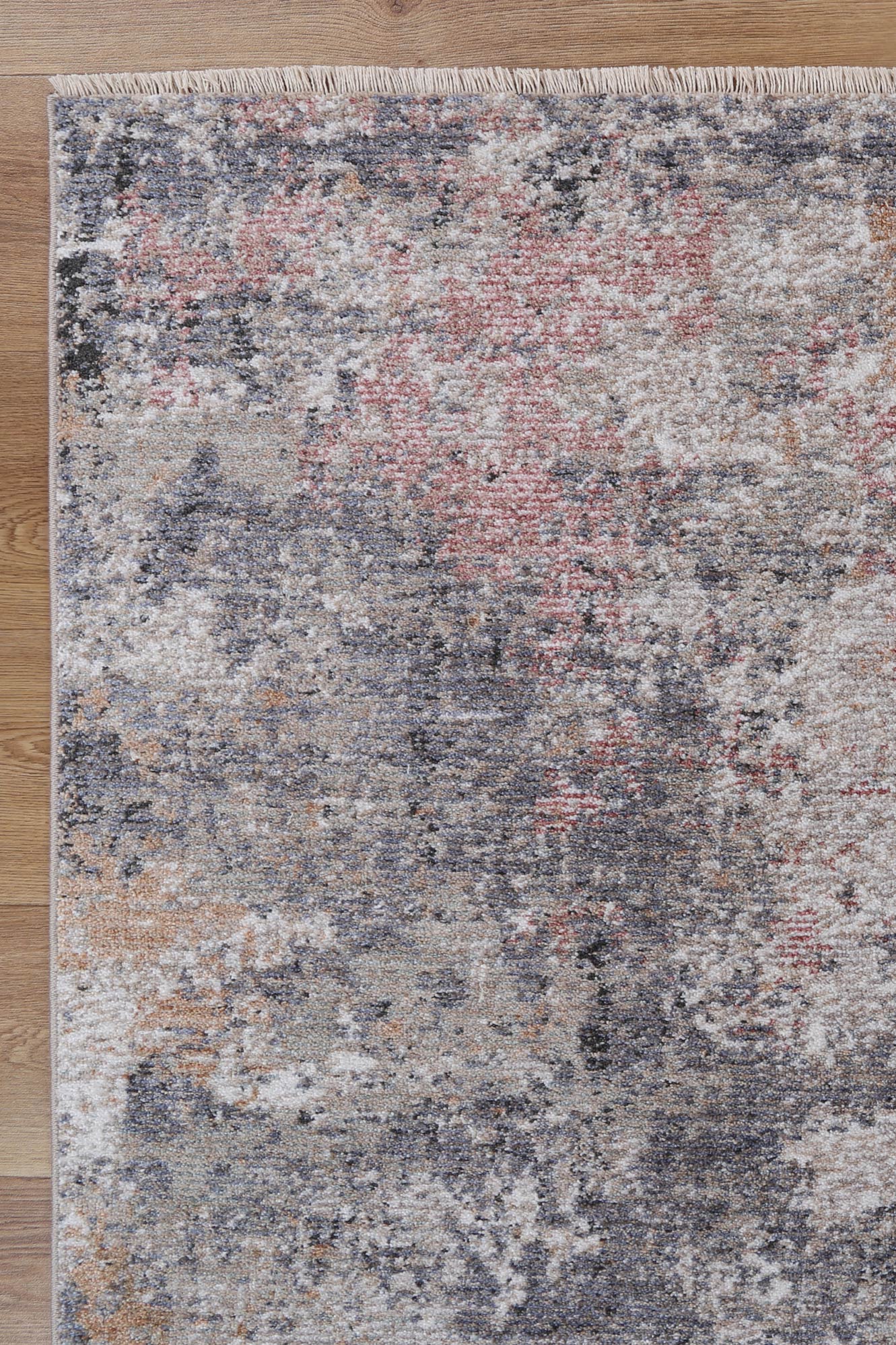 Multicolored area rug with a textured pattern on a wooden floor.