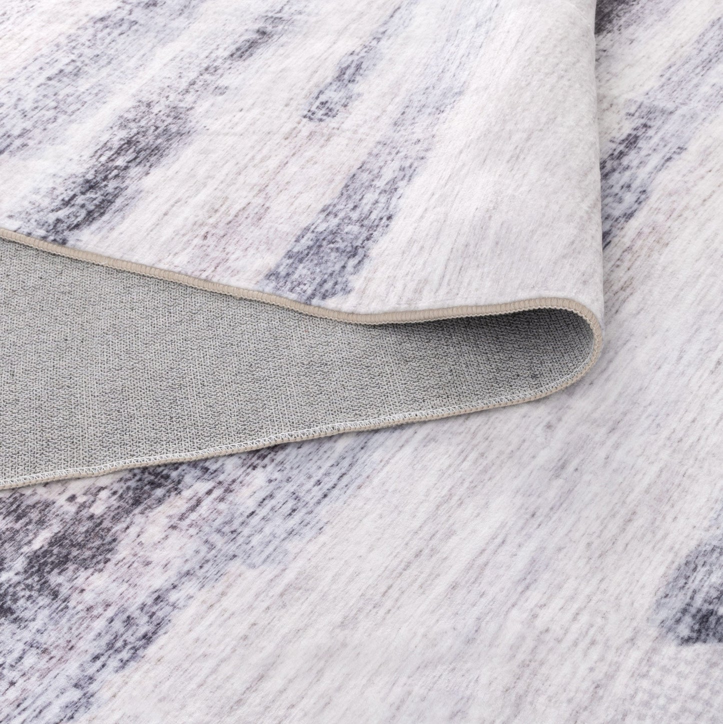 Close-up of a textured rug with a neutral color palette on a wooden floor.