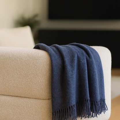 Navy Blue throw blanket draped over a beige sofa in a living room setting.