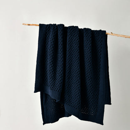 Navy textured blanket draped over a wooden stick on a white background