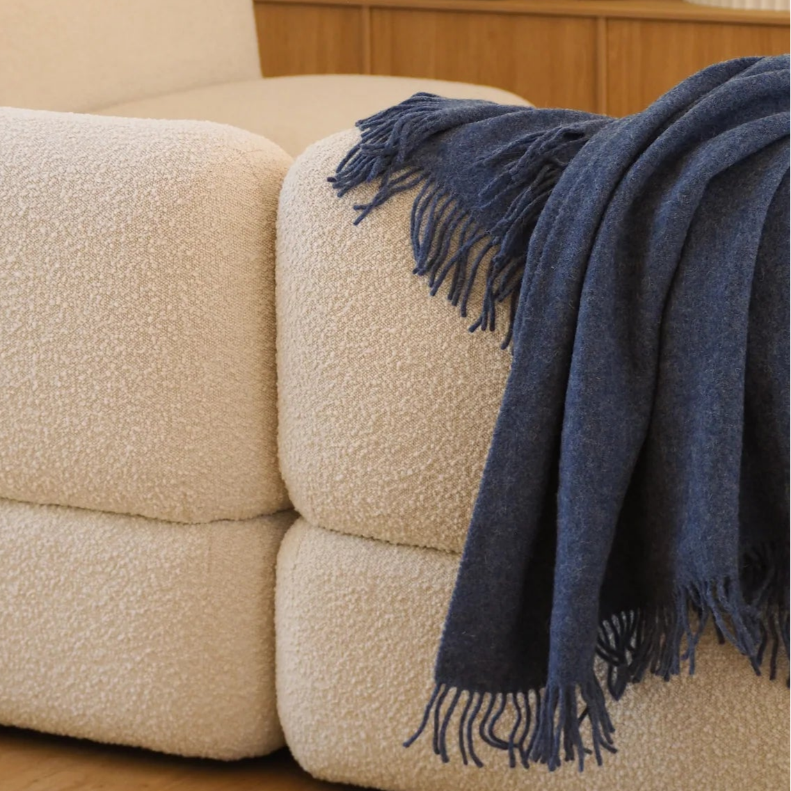 White boucle sofa with a navy blue blanket in a living room setting