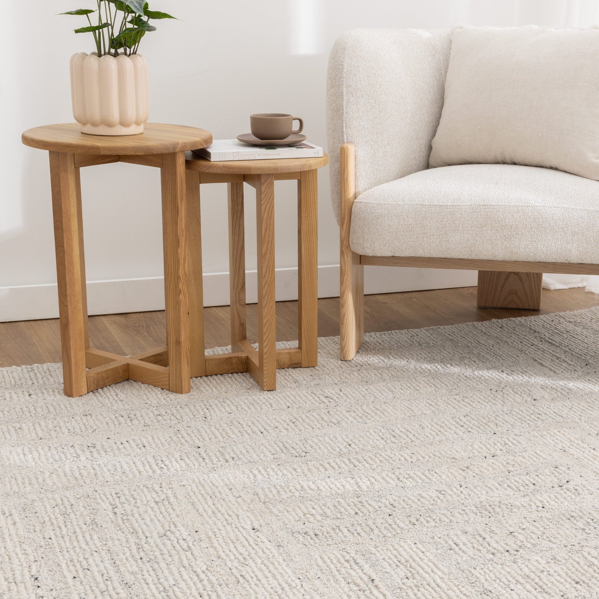 Two wooden side tables with a plant and small bowl in a living room setting.