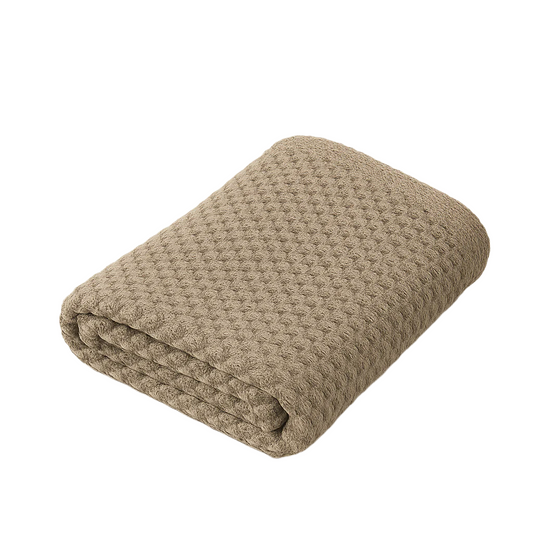 Folded beige textured blanket on a light beige background