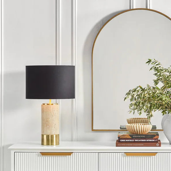 Console table with decorative items including lamps, a plant, and baskets against a white wall.