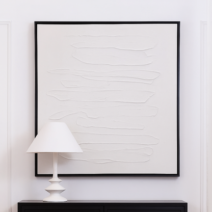 White canvas painting in black frame styled on white wall with black console table