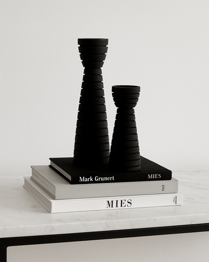 Black carved wood candle holders styled on stack of books on marble console table | Mirra Interiors