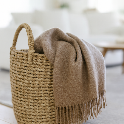 Woven basket with a brown blanket on a light wooden floor