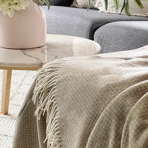 Round marble coffee table with a vase and flowers in a living room setting.