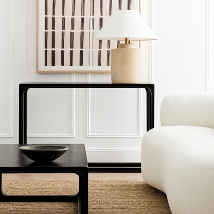 Modern living room with a black side table, white lamp, and white sofa.
