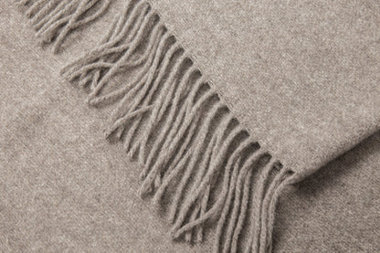 Close-up of a beige blanket with fringes folded texture