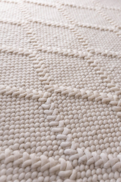 Close-up of a textured beige rug with a wavy pattern